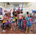 a group of people holding balloon shapes and making silly faces