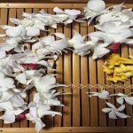 Color photo of 3 assorted lei in slatted wooden tray
