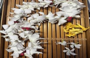 Color photo of 3 assorted lei in slatted wooden tray