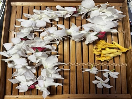 Color photo of 3 assorted lei in slatted wooden tray