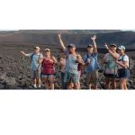 group of people hiking in a rocky landscape with mountains in the background