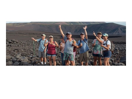 group of people hiking in a rocky landscape with mountains in the background