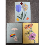 Three handmade cards, one with folded paper tulips, one with stamped and colored daisies, and one with a rabbit in the rain with two umbrellas