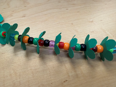 green paper flowers strung with colorful beads