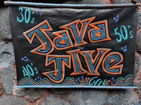 Black sign with the words Java Jive in blue and orange against a rock wall. The numbers 30s 40s and 50s are also on the sign.