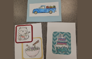 Three handmade cards, one with a truck and fruit, one with a cat eating saimin and a saimin bowl with chopsticks, and one with a birthday cake with a blue background