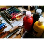 art supplies including colored pencils and paints on a table