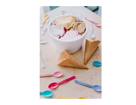 bowl of ice cream on a table with spoons and cones scattered around