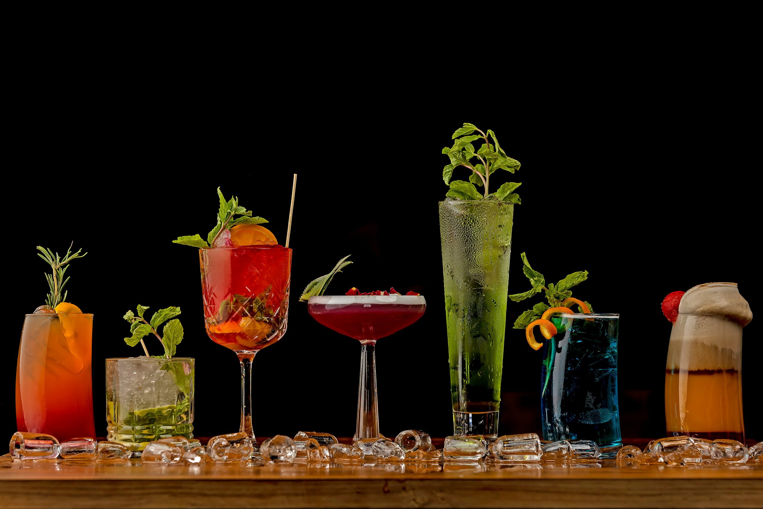 A display of various colorful mocktails using unique cups stationed on a table