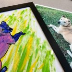 Framed colorful pet portrait next to a photograph of a dog used as the painting reference.