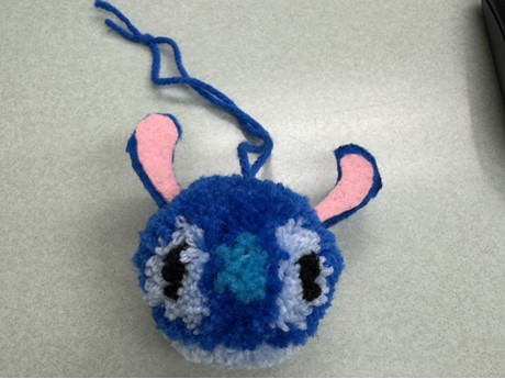 Yarn pompom designed like stitch on blank background