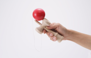 picture of a hand holding a red and tan wooden kendama toy
