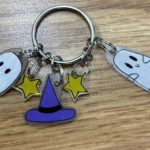 A keychain with five charms: 2 white ghosts, 2 yellow stars and one purple hat attached to one keyring