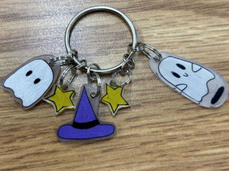 A keychain with five charms: 2 white ghosts, 2 yellow stars and one purple hat attached to one keyring