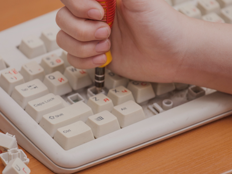 hand holding a tool to extract keys from a computer keyboard