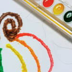 Watercolor salt painting of a pumpkin and tray of paint.