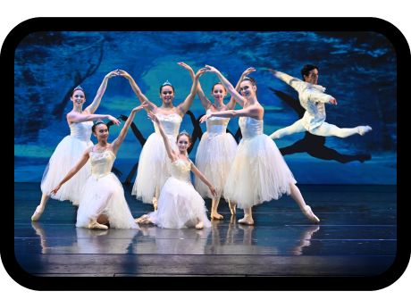 6 female and 1 male ballet dancers wearing white costumes on stage in front of blue image background