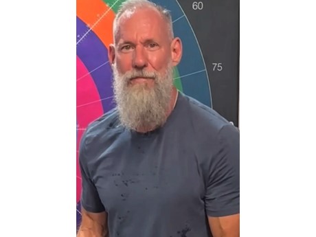 photo of a man with a medium length gray beard wearing a blue-gray tee shirt