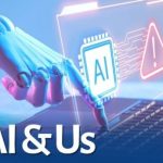 A robotic hand touches a laptop keyboard, displaying a digital interface with an AI icon and a warning sign above the text “AI & Us.”
